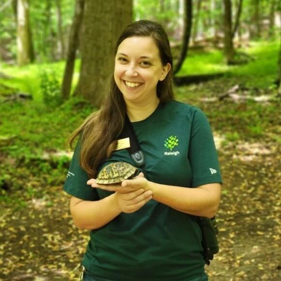Sara holding a turtle in a wooded area